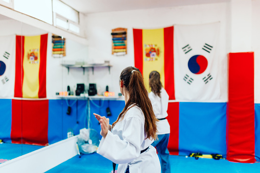Two young women practice taekwondo in a training center