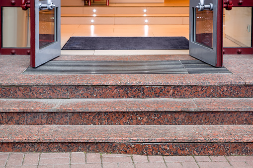 marble staircase with granite steps to entrance door on store with glass, threshold with doormat at facade of building , nobody.