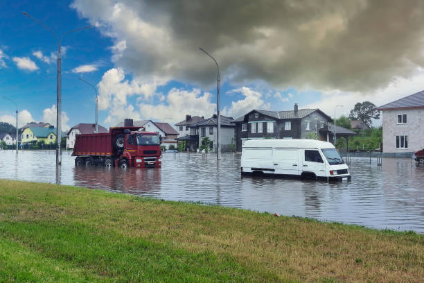 車は浸水した道路で大雨に乗ります。大雨の後、街の通りが浸水した。水の洪水のレベルを表示します。洪水で運転する車 - sunken ストックフォトと画像