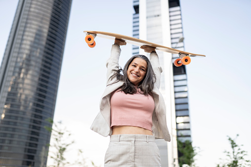 mature woman, businesswoman with skateboard happy in town