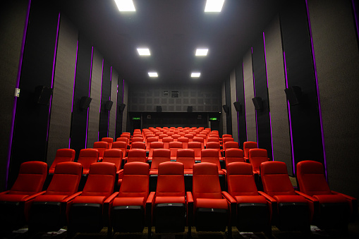 A row of neat red chairs in the unfinished theater