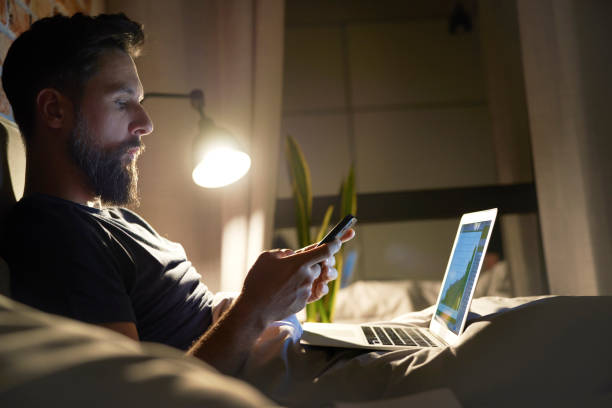 istock Side view of man working in bed at night 1326470272