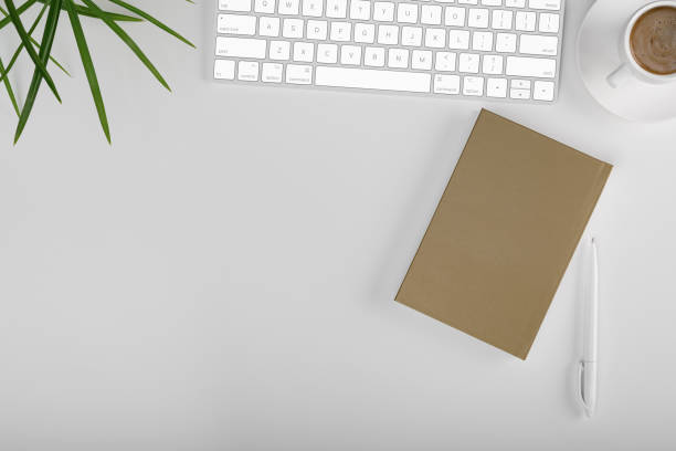 istock Top view office table desk. Workspace with blank, office supplies, pencil, green leaf, and coffee cup on white background. 1326471198