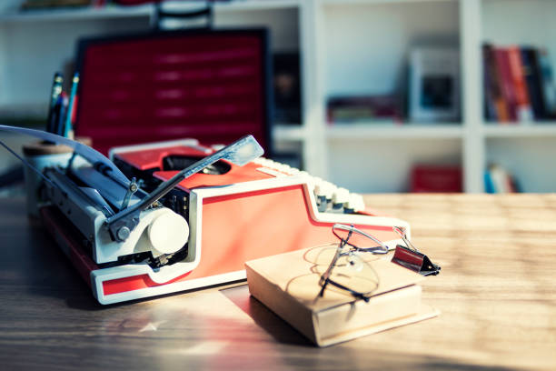 Retro typewriter and old vintage book and eyeglasses on wooden table