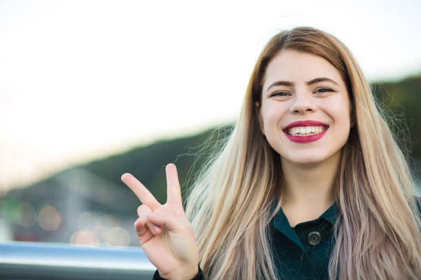 istock Lifestyle shot: pretty happy woman with red lips showing peace hand gesture. Space for text 1326474096