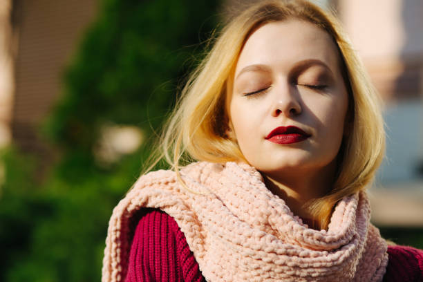 istock Tender blonde model with red lips wearing pink scarf posing in rays of sun. Empty space 1326474155