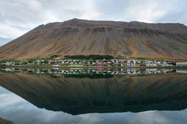 les maisons, les arbres et une pente raide se reflètent dans la surface miroir de la baie par une journée calme et venteuse - flattop mountain photos et images de collection