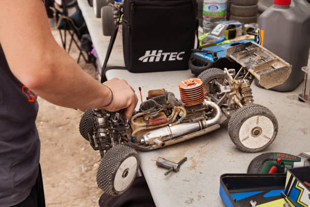 uomo che lavora sul modello di auto buggy radiocomandato, motore a combustione interna, durante la scala del campionato 1/8 off road il 26 aprile 2015 a riolo terme, ra, italia - gear machine part wheel four objects foto e immagini stock