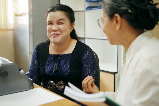 Feliz persona ciega asiática mujer con máquina de escribir braille vintage o Brailler para personas con discapacidades de visión, trabajando y hablando con la mujer colega senior en el lugar de trabajo de la oficina. photo