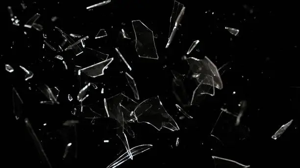 Studio full-frame wide plate shot of window glass pane shattering and breaking on black background. Real smash explosion at high speed as action concept template and overlay element.