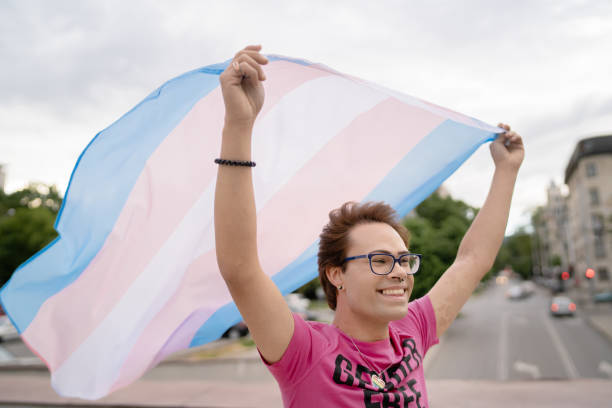 man holding transgender flag in the air - flag rainbow gay pride flag gay man imagens e fotografias de stock