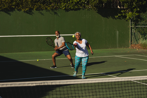 Senior african american couple playing tennis on tennis court. retirement and active senior lifestyle concept.