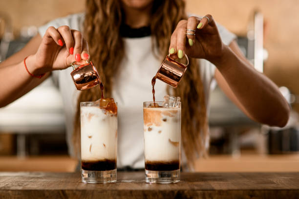 process of making macchiato with syrup. woman pours coffee from cups into glasses - espresso women cup drink imagens e fotografias de stock