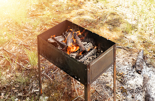 Grill with black coals and fire for bbq on grass.