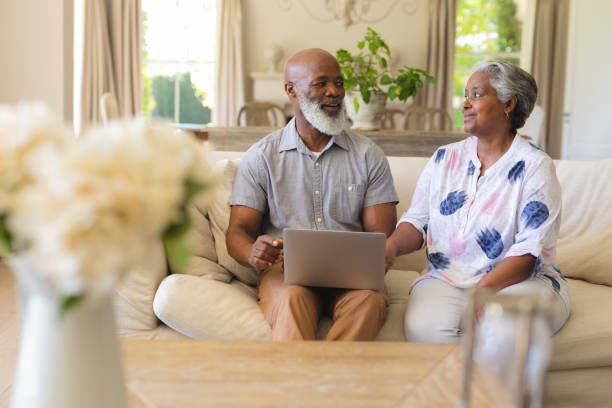istock Senior african american couple sitting on sofa using laptop and smiling 1326494917