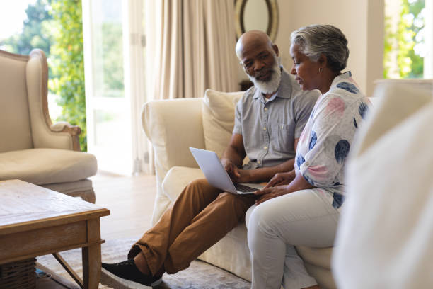 istock Senior african american couple sitting on sofa using laptop and talking 1326494930