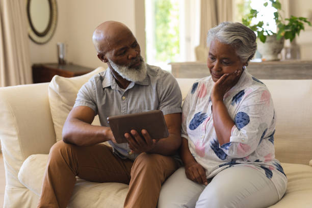 istock Senior african american couple sitting on sofa using tablet 1326495032