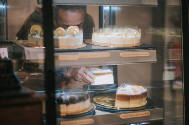 asian chinese senior man retrieving slice of cake dessert to serve to his customer from kitchen counter