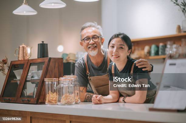 Asian Chinese Senior Male Cafe Owner And Her Daughters Looking At Camera Smiling At Coffee Shop Counter Stock Photo - Download Image Now