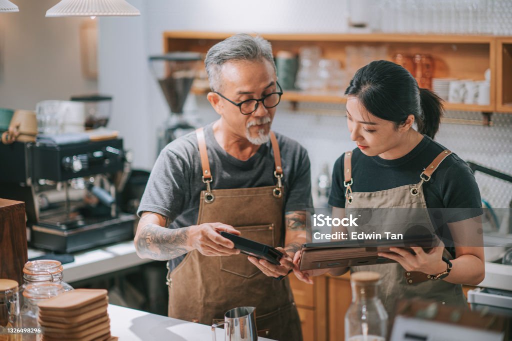 asian chinese senior man owner and daughter using digital tablet at bar counter table Small Business Stock Photo