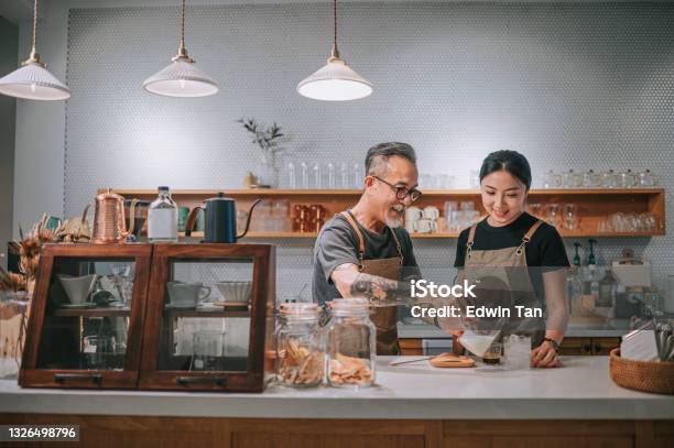 Asian Chinese Senior Male Barista Teaching His Daughter Making Coffee At Cafe Bar Counter Stock Photo - Download Image Now