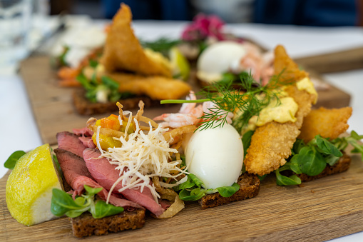 A close up view of delicious Smørebrød sandwiches on a wooden platter as a typical Scandinavian breakfast