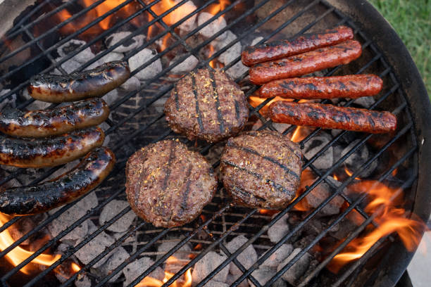 赤身の草は牛肉ハンバーガーとブラットヴルスト、炎と炭火グリルのソーセージ、裏庭のバーベキュー、夏、屋外の追求 - barbecue grill broiling barbecue vegetable ストックフォトと画像