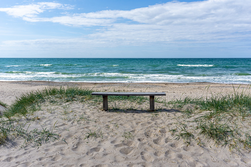 A vertical view of a wooden bench on an idyllic secluded empty beach