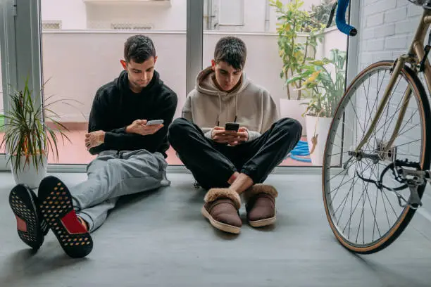 Photo of young people at home with mobile phones sitting on the floor