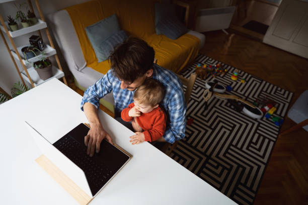 istock Young modern Caucasian father working at home while holding his baby son 1326507768