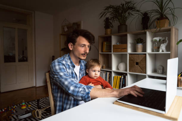 istock Father working at home while holding his baby son 1326507780