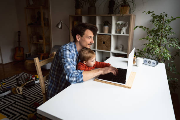 istock Handsome father working at home while holding his baby son 1326507785