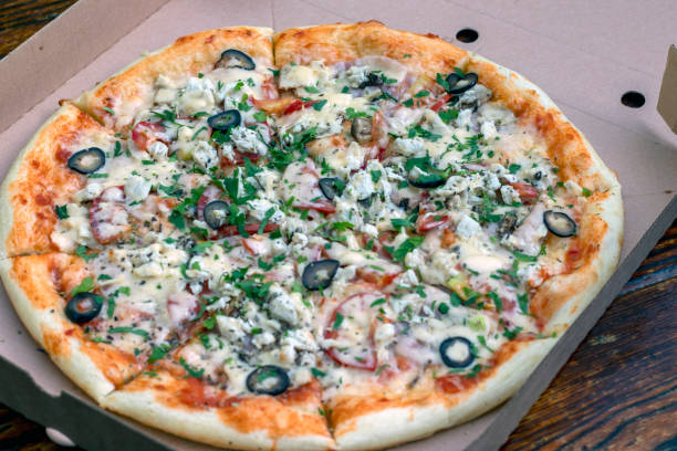 istock Pizza in a cardboard delivery box on the table. View from above. Pizza delivery. 1326508052