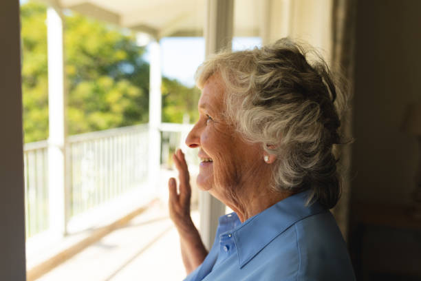 istock Senior caucasian woman looking through window and smiling 1326509898