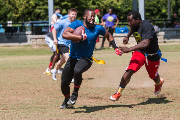 Man Carrying Ball Avoids Defender In Recreational Flag Football Game Atlanta, GA, USA - June 1, 2019:  A man carrying the ball tries to run away from a defender in a recreational league flag football game played at the Old Fourth Ward Park on June 1, 2019 in Atlanta, GA. georgia football stock pictures, royalty-free photos & images