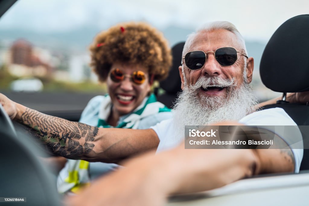 Happy senior couple having fun driving on new convertible car - Mature people enjoying time together during road trip tour vacation - Elderly lifestyle and travel culture concept Senior Adult Stock Photo