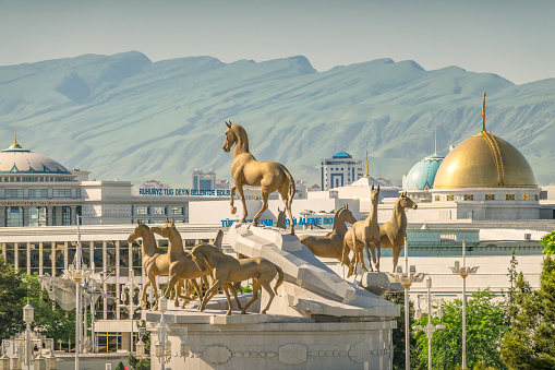 Cityscape of downtown Ashgabat Turkmenistan with the monument to ten Akal Theke horses, on a sunny day. The monument was opened in 2001, on the 10th anniversary of the independence of Turkmenistan from the Soviet Union, artist uknown.