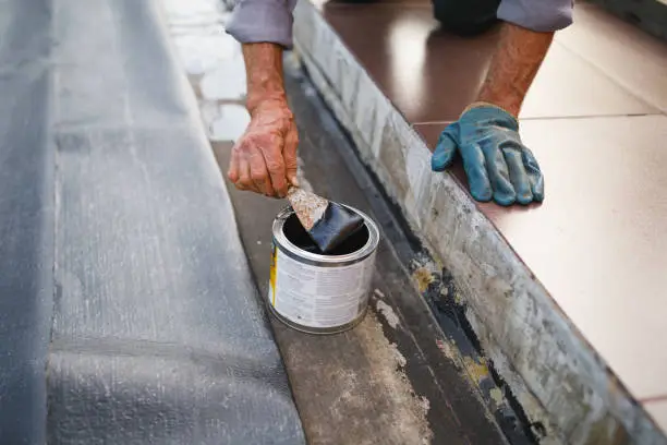 man working with waterproofing material, close-up view