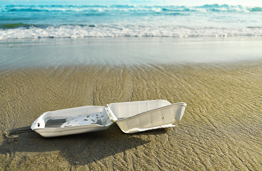 Styrofoam disposable food box on the beach, pollution, waste on sand beach