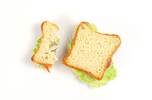 istock Ham sandwiches on a white background. Half-eaten and whole ham sandwich with ham, red tomatoes, green lettuce, dill and cream sauce. 1326530785