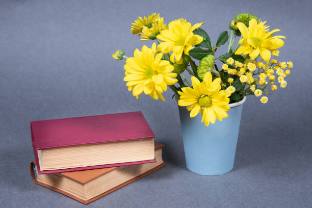 istock Yellow flowers and books on gray background. 1326539350
