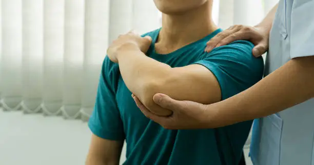 Photo of Young man with body aches and fatigue with doctor-assisted care and medical and physical therapy health concepts