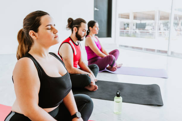 Plus size young hispanic woman sitting while practicing meditation during yoga session in Latin America Plus size young hispanic woman sitting while practicing meditation during yoga session in Latin America fat mexican man pictures stock pictures, royalty-free photos & images