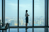 Businesswoman looking at city skyline through office window