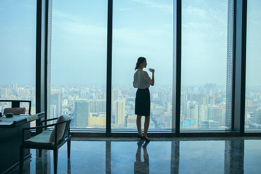 Businesswoman drinking coffee and looking out the window in an office
