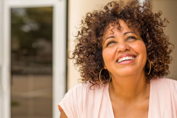 Portrait of a mature woman laughing. Mixed race mature woman with curly hair  smiling. latin woman stock pictures, royalty-free photos & images