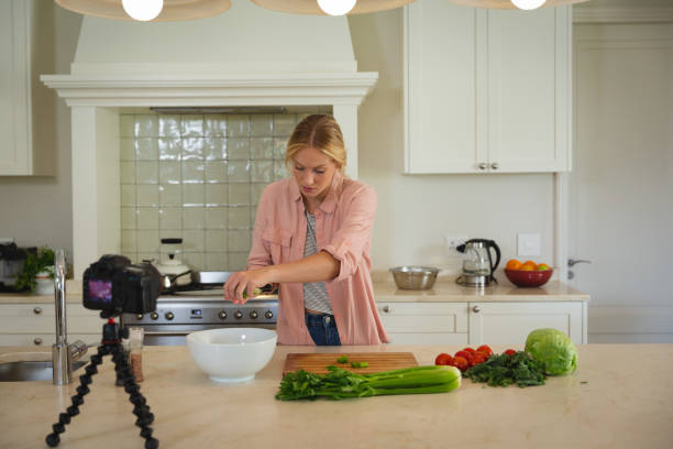 istock Caucasian woman in kitchen preparing food and using camera, making cooking vlog 1326550853