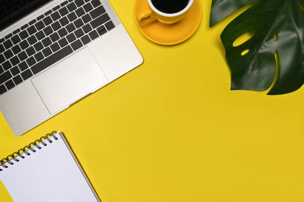 istock Laptop computer, coffee cp and notebook on yellow background. 1326557071