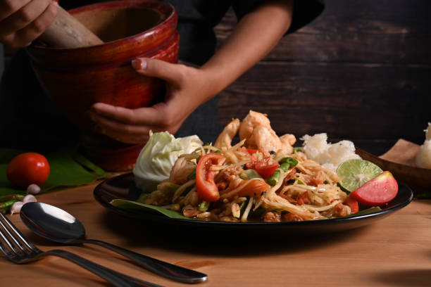 Cropped shot woman making spicy papaya salad with mortar. Cropped shot woman making spicy papaya salad with mortar. tam o'shanter stock pictures, royalty-free photos & images