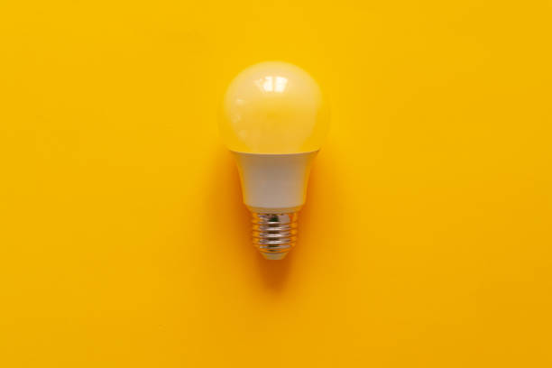 Light bulb on yellow paper background top view photo